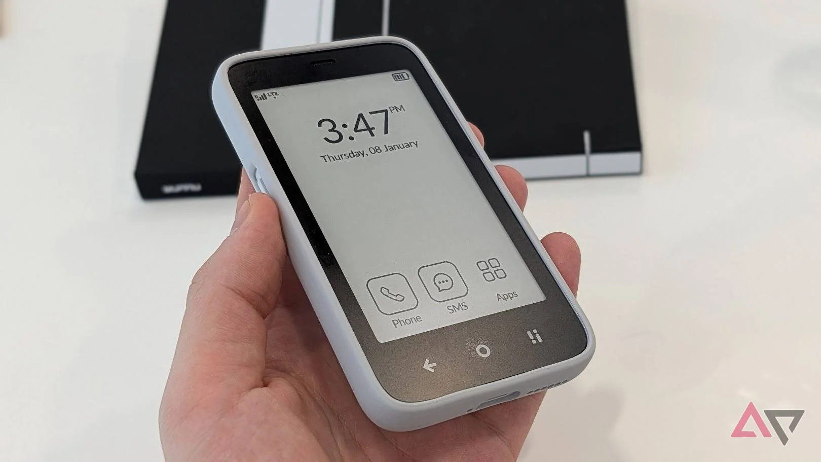 black and white e-paper smartphone showing time and apps